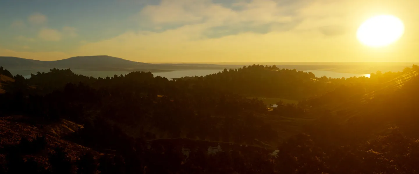 Golden sunlight over a forest, lake and distant ridgelines.